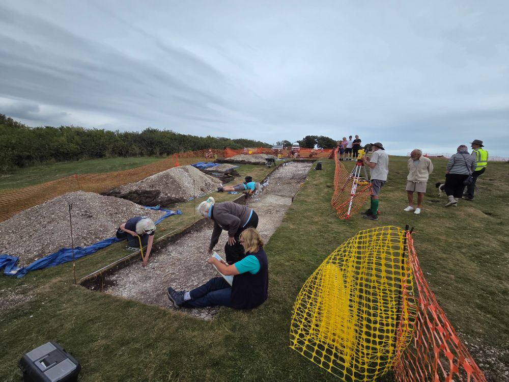 An archaeological trench cut down to chalk natural with archaeologists investigating prehistoric features