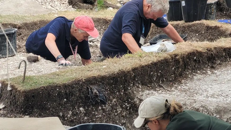 Archaeologists excavating in a trench