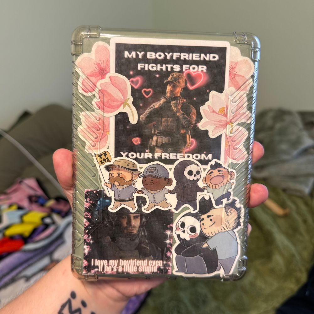 Green kindle decorated with stickers of characters from call of duty: modern warfare II and pink flowers 