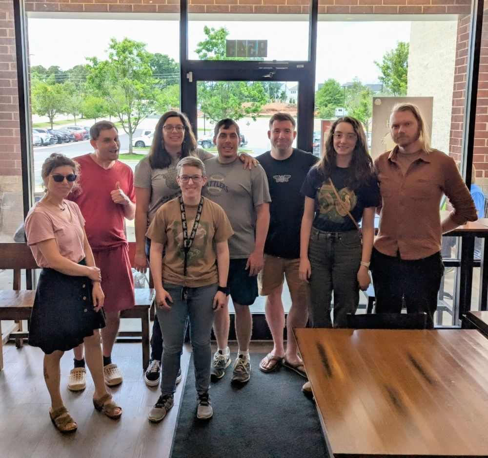A group of 8 people pose for a photo together