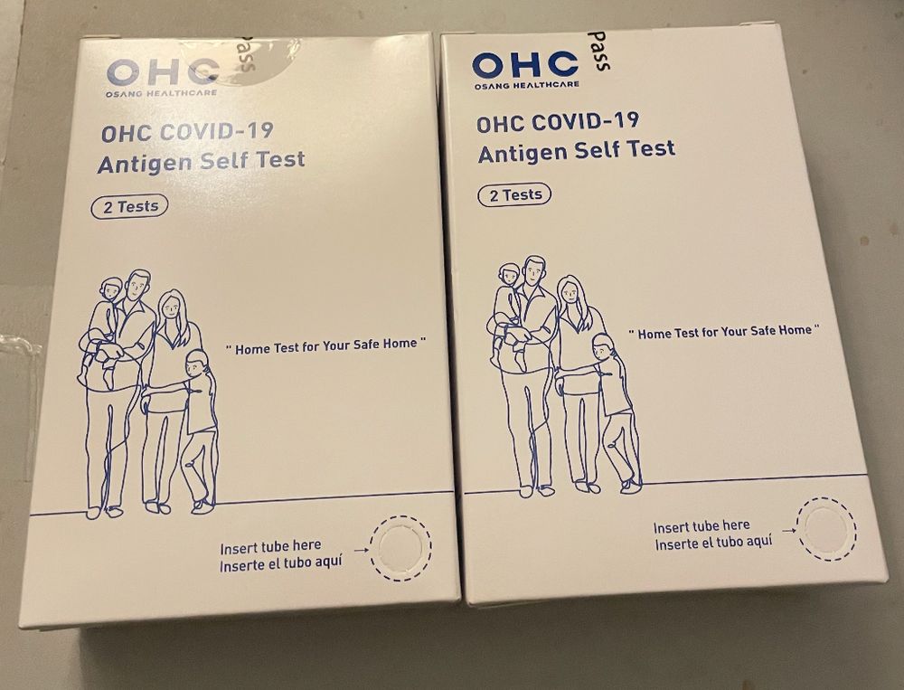 Pic of 2 boxes of expired Covid tests with line drawing of family on the packaging 