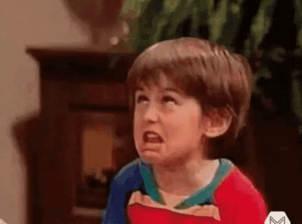 a young boy is making a funny face while sitting in front of a television .