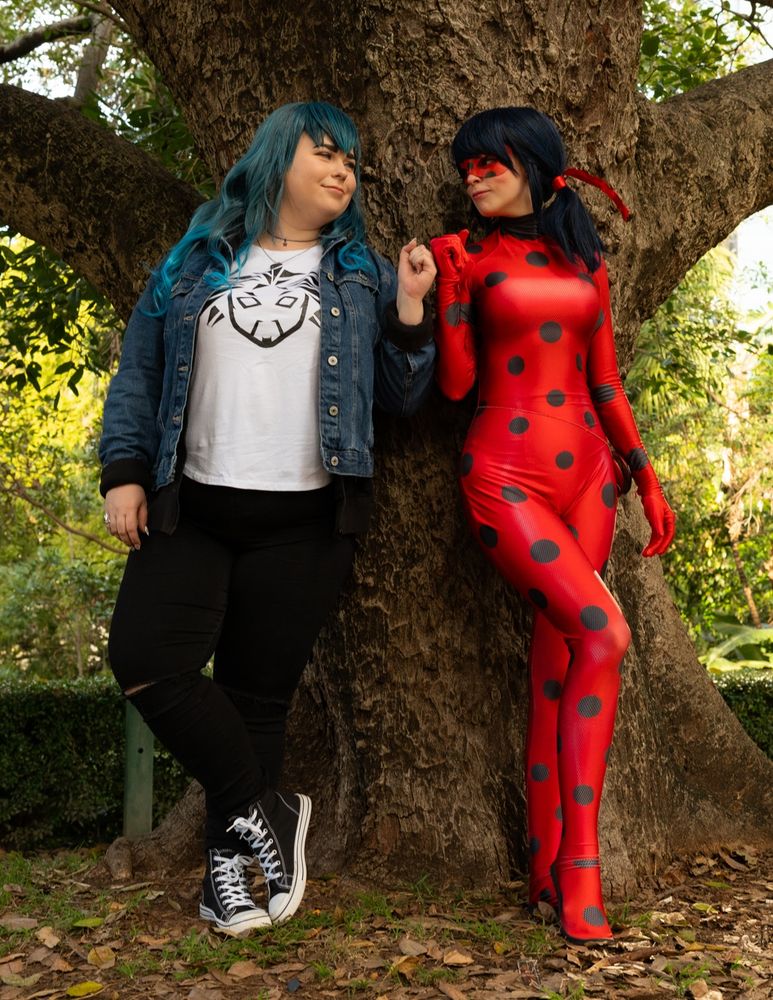 Luka and Ladybug fistbump while leaning against a tree
