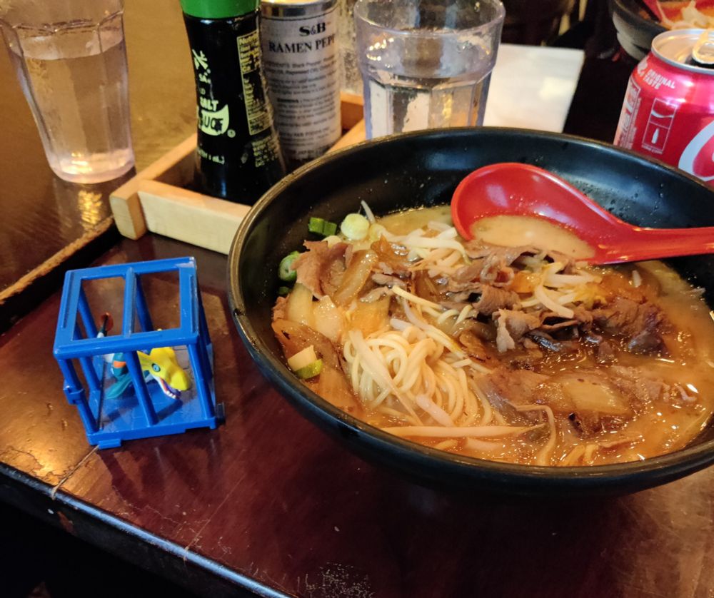 Beef Sukiyaki Ramen next to a Seadramon in a blue cage aka gay baby jail
