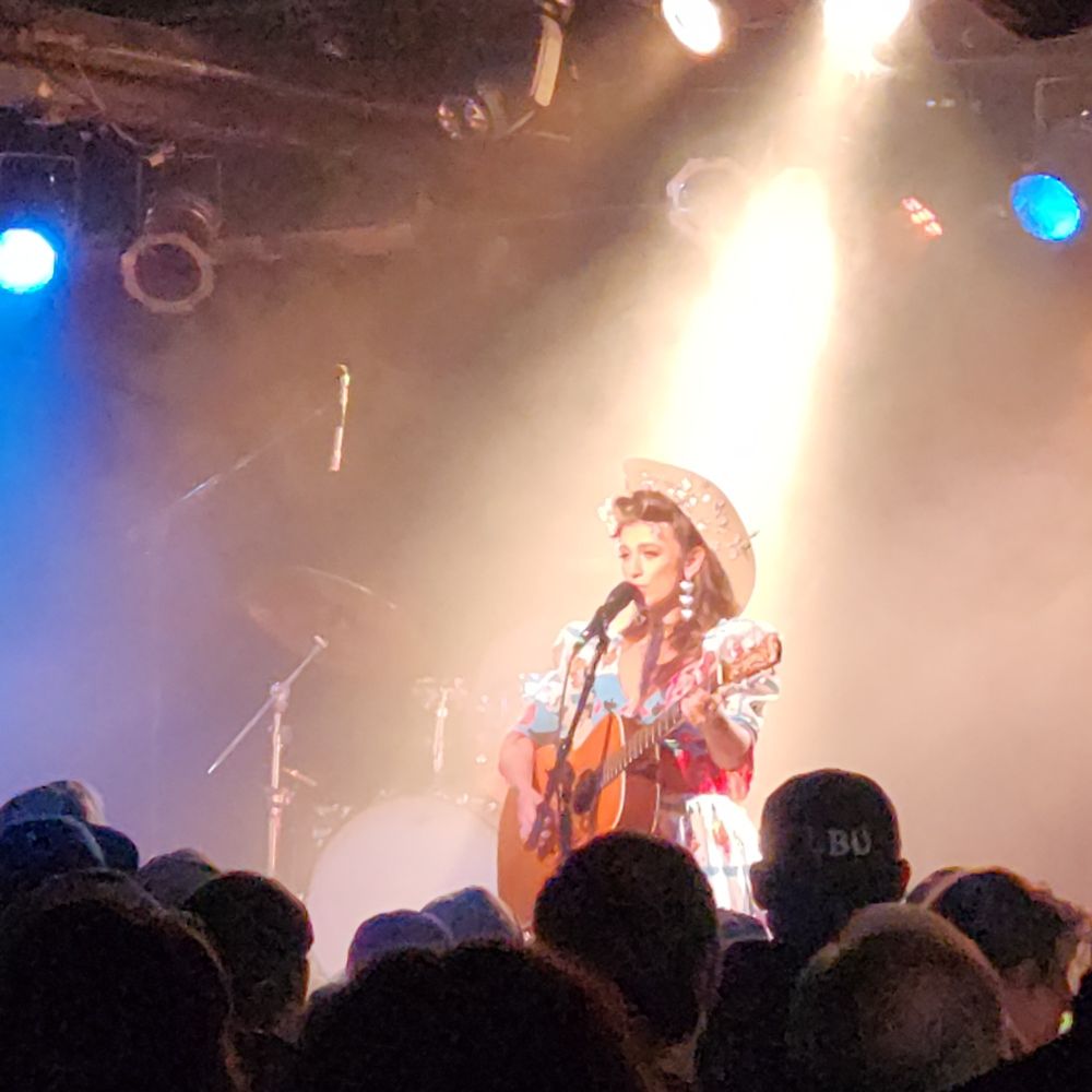 Sierra Ferrell, with her guitar, washed in soft stage lights in Chicago.