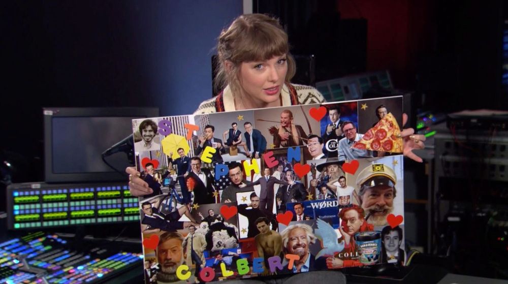 A screenshot of taylor swift on the Colbert show holding up a poster of images of Stephen at various points in his career and including a photo of a pizza and a golden football. 