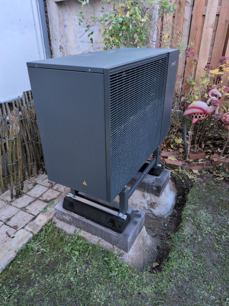 Ein Außengerät für eine Wärmepumpe neben einem Metallflamingo