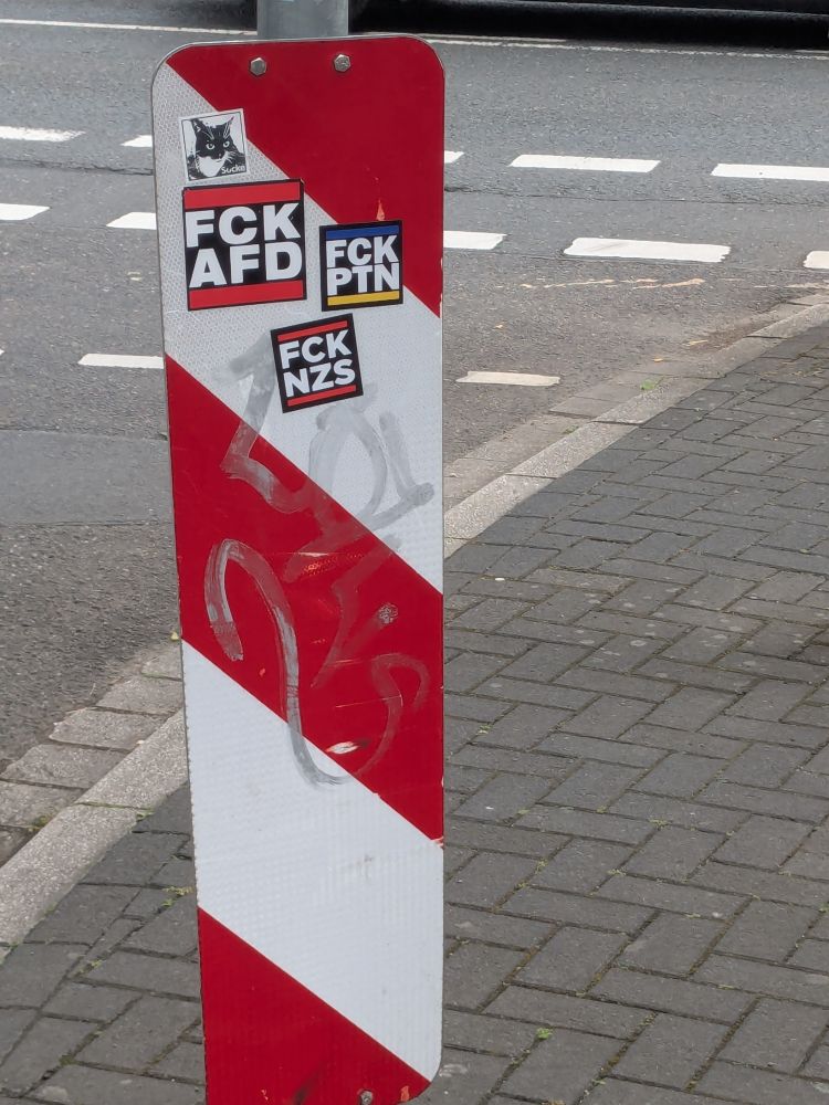 Eine gestreifte Warnbake (rot, weiss) mit FCKAFD Aufkleber