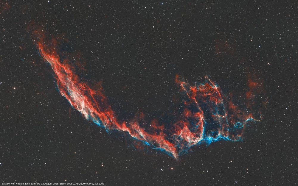 Cropped image of the Eastern Veil Nebula
Thin red nebulosity with blue lower edge stretching from top left towards bottom right in a shallow bowl shape, a prominence rises up on the left hand side.
The nebula was discovered on 5 September 1784 by William Herschel.