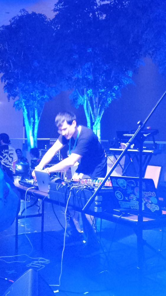 Musician Foozogz performing onstage at TrotCon 2025, but washed in blue light glare