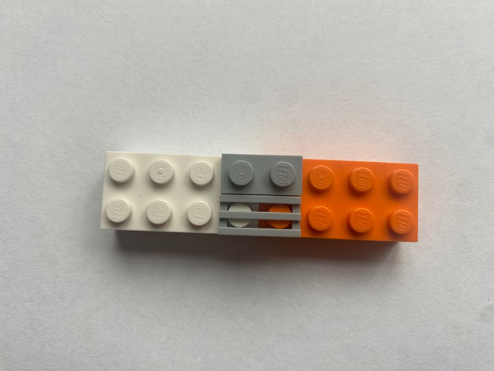Bild einer DNA-Doppel-Helix, gebaut aus Legosteinen, gezeigt werden die verbundenen Basenpaare bestehend aus zwei Legosteinen die die Basen repräsentieren und zwei Steinen die diese verbinden.