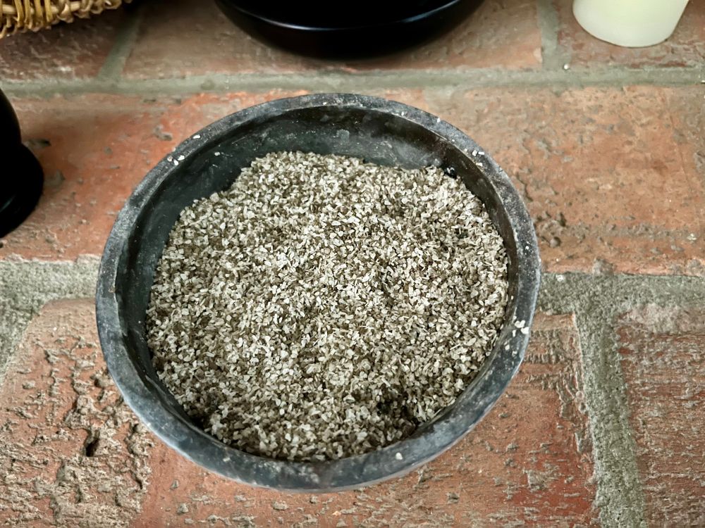 A bowl of homemade black salt on a brick altar. 