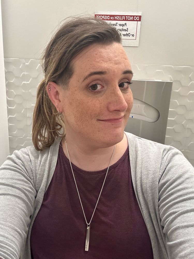 Erin taking a bathroom selfie with her hair in a ponytail, showing the undercut