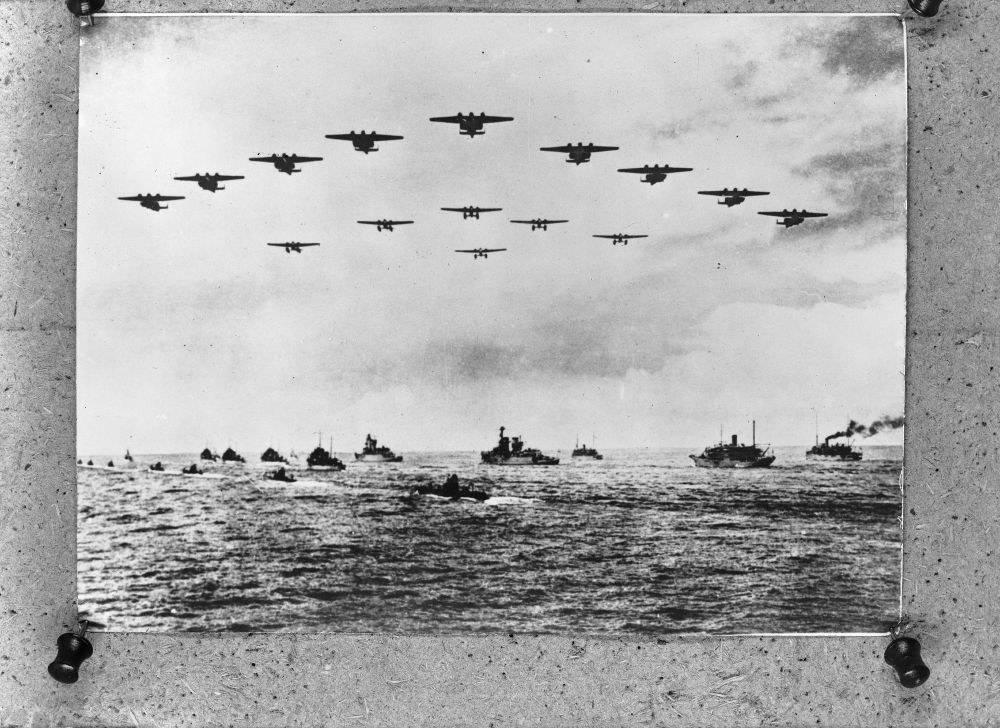 A formation of Dutch Navy Dornier Do 24s followed by Fokker torpedo floatplanes pass over a Dutch Navy fleet of ships. Photo pinned to a cork board.