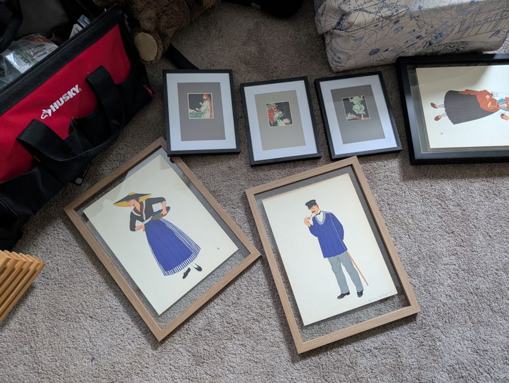 Framed prints on a carpeted floor. A man and a woman, each dressed in the same bright shade of blue, wearing traditional European costumes. I think they're supposed to be from auvergne 