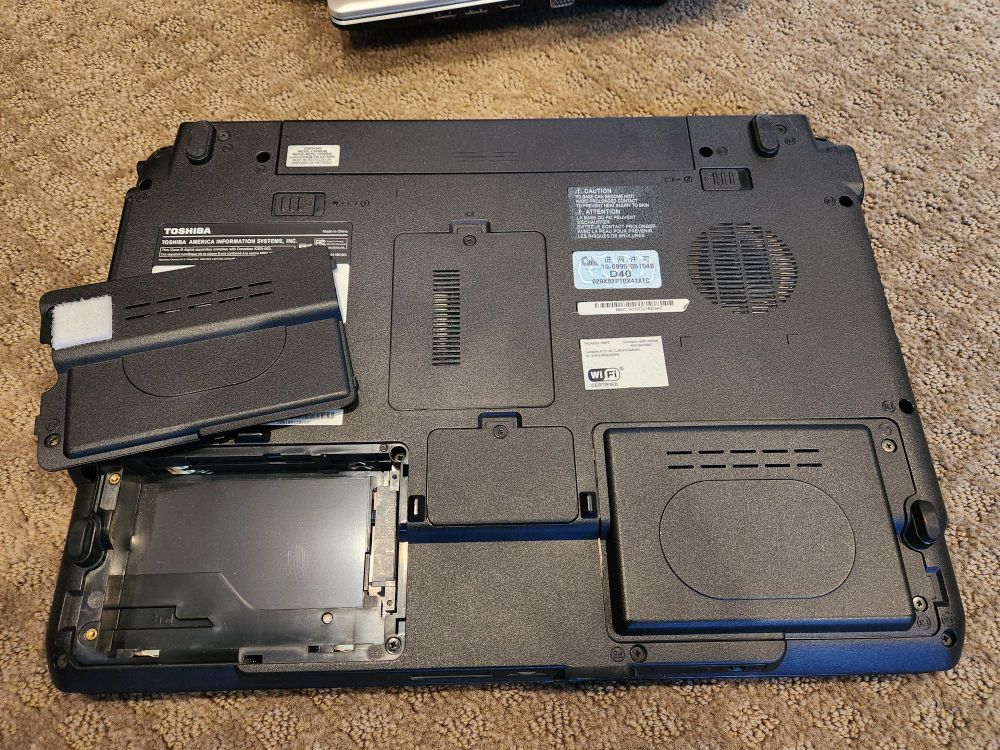 The back side of an old laptop computer, where all of the components are easily accessible with individual covers
