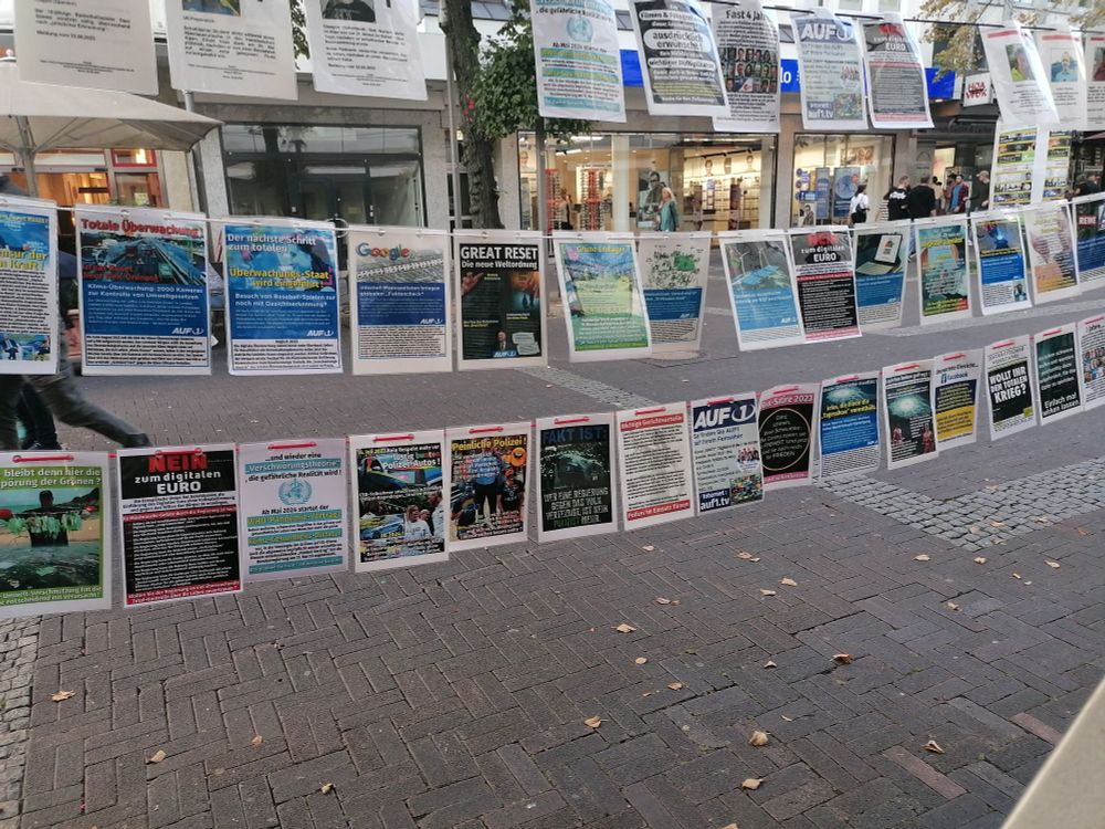 Foto von der "Ausstellung", Schnüre mit a4 blättern, Themen sind zb. "great reset", "nein zum digitalen Euro" oder "totale Überwachung"