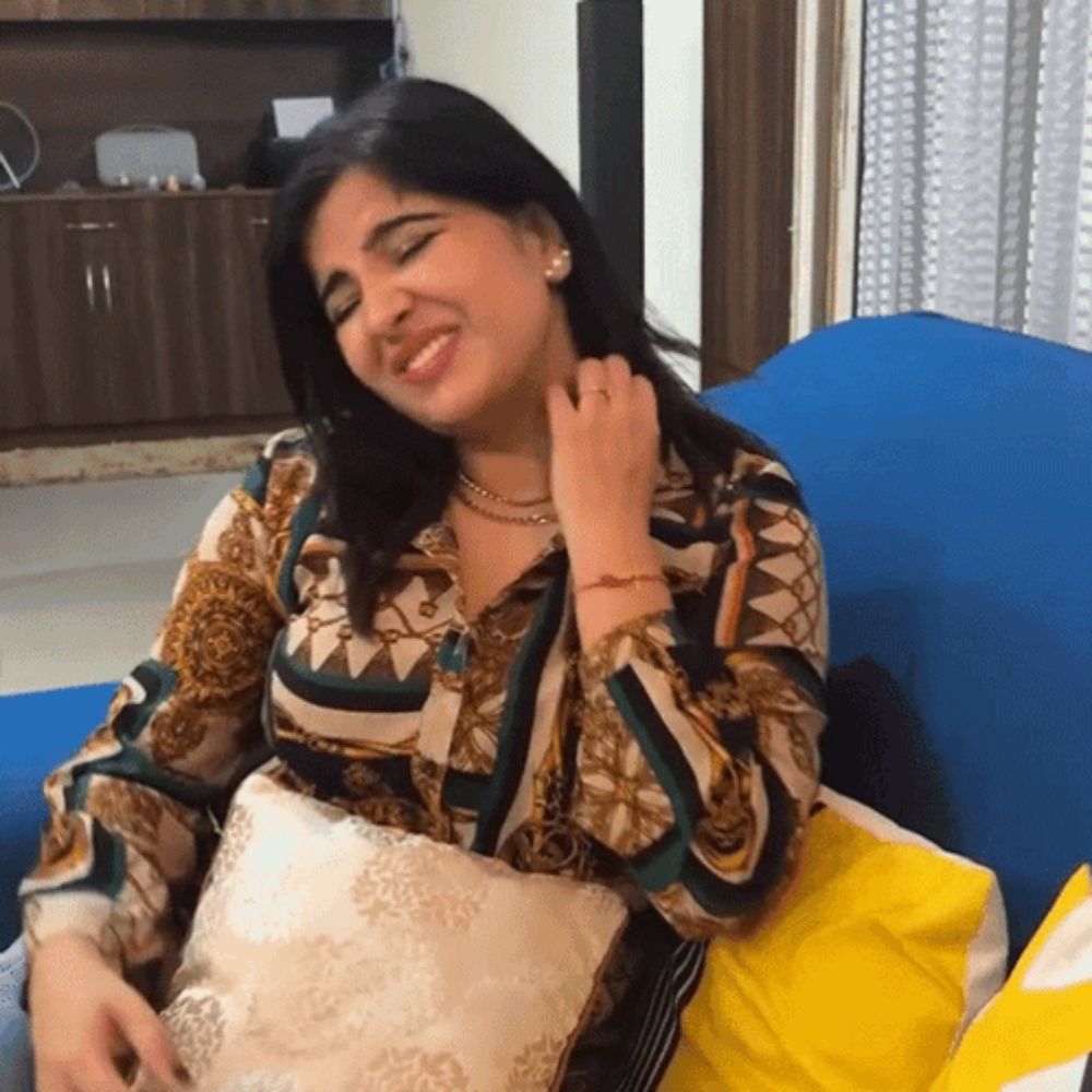 a woman is sitting on a blue couch with a pillow and smiling