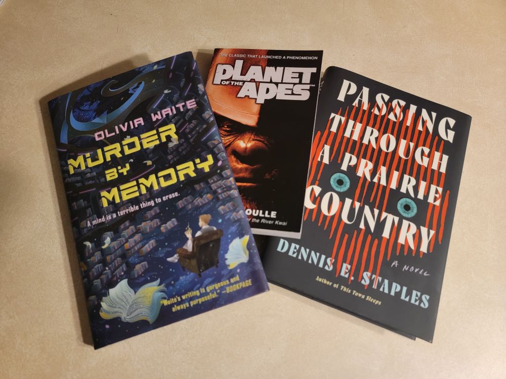 Murder by Memory by Olivia Waite, Planet of the Apes by Pierre Boulle, and Passing Through a Prairie Country by Dennis E. Staples.