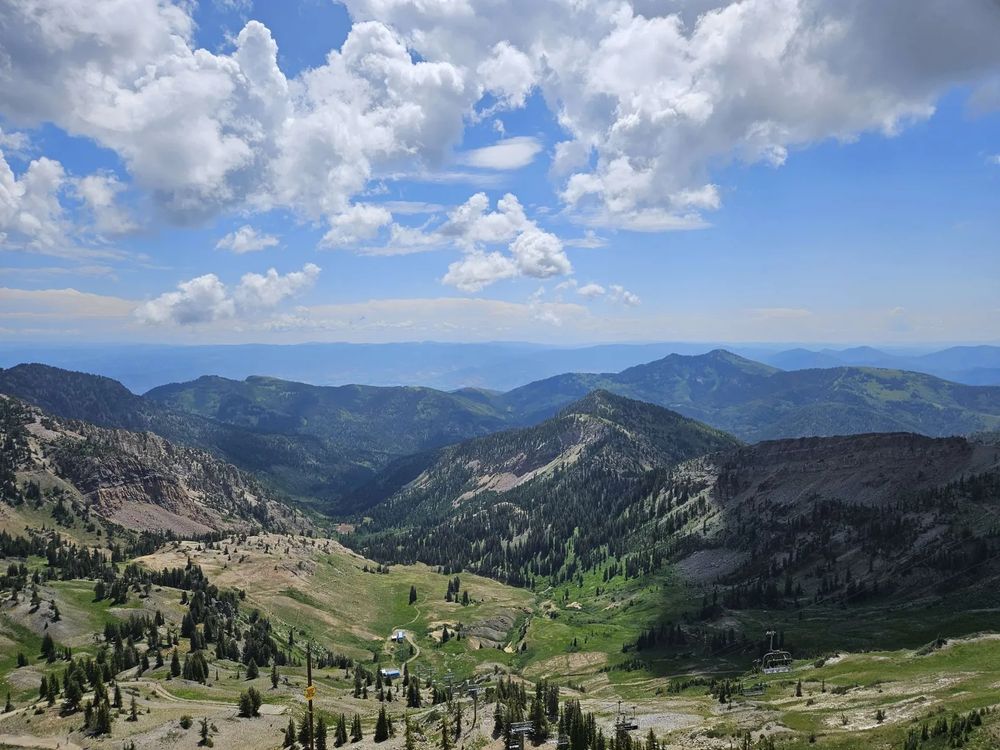 A landscape shot out over the valleys and mountains, showing a sky with clouds and mountains as far as the eye can see.
