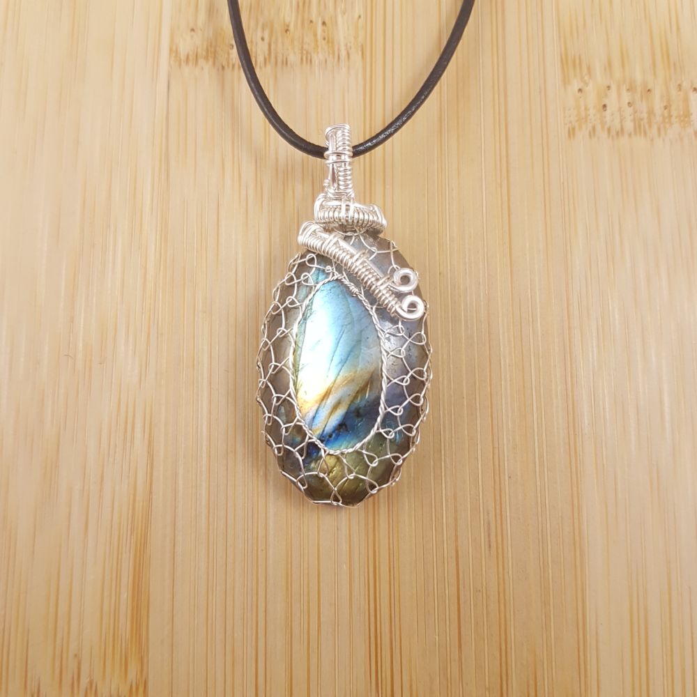 Small green, bronze, and blue oval labradorite pendant netted in silver wire.