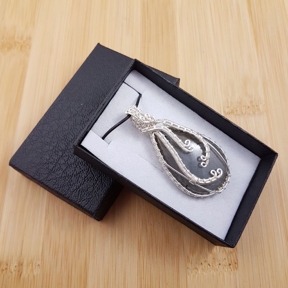 Large blue labradorite drop pendant wrapped in wavy silver wire, sitting in black and white gift box.
