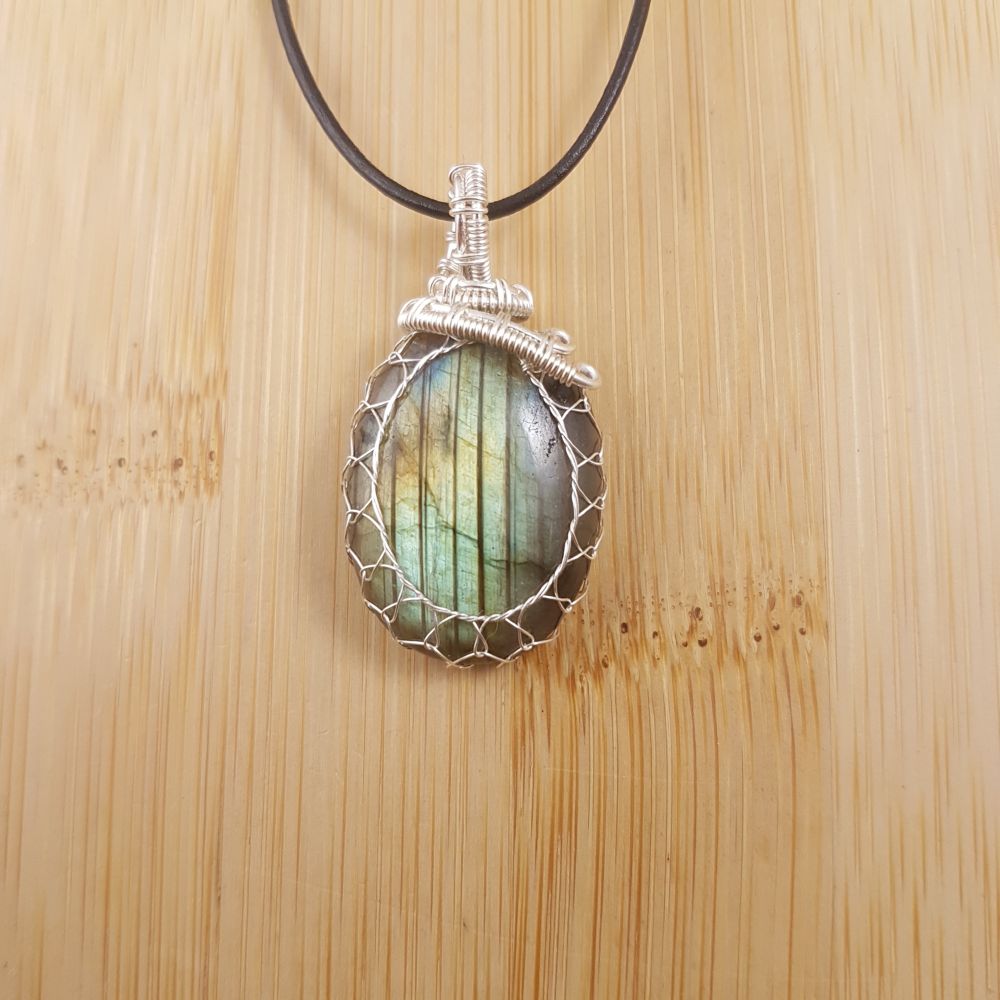 Small green oval pendant with vertical stripes, netted in silver wire.