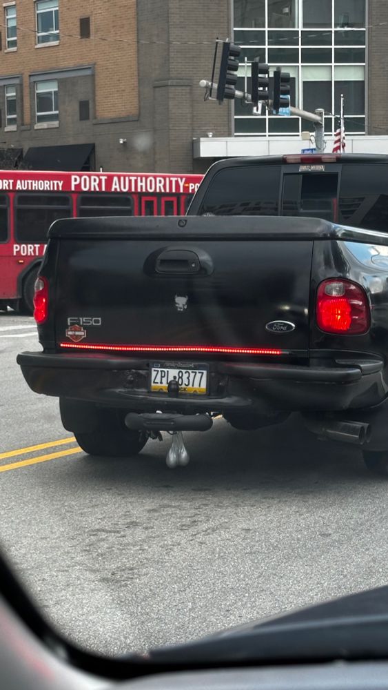 Silver truck nuts hanging off of a black pickup truck. 