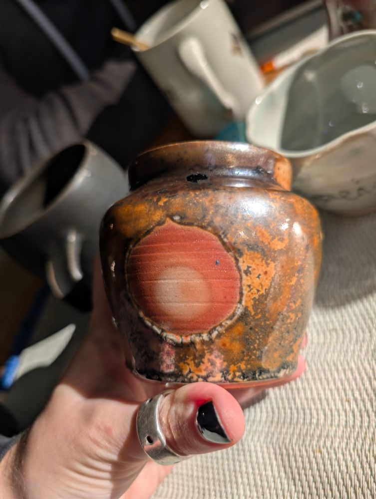 A small ceramic vase, glazed with a Malcom Davis Shino on the exterior which resulted in a warm mottled, highly metallic/reflective sheen.