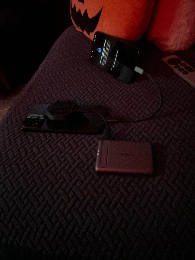 Two iPhones connected by a cable, one shows a timer with 2 hours remaining. The other has a fan connected to the back via MagSafe, powered by a battery it is connected to.