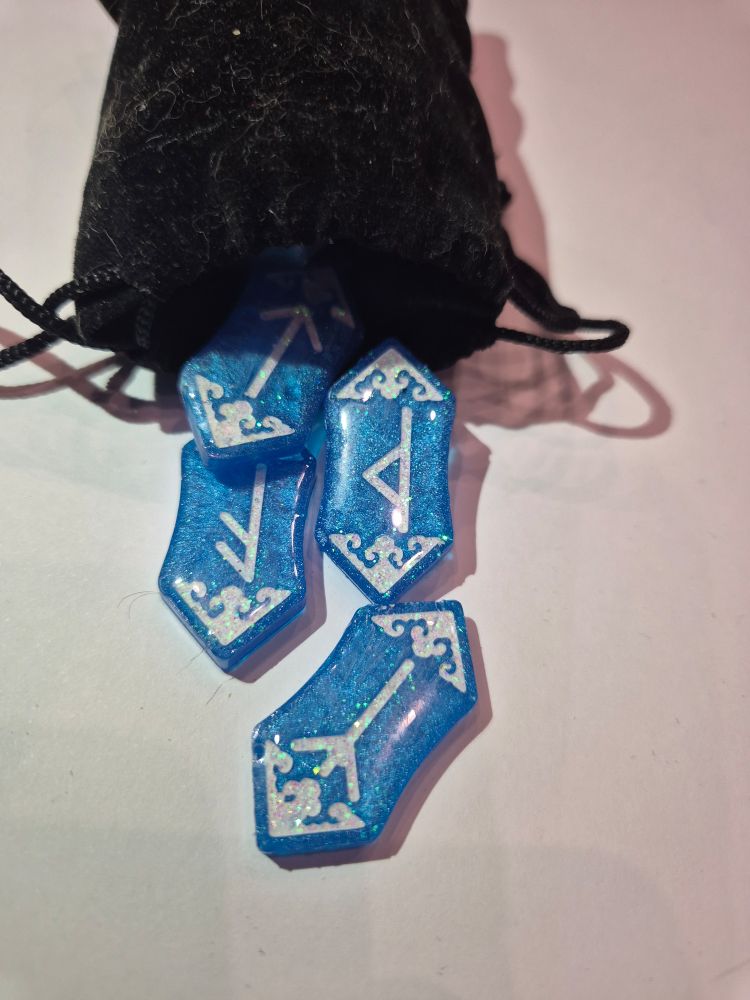 Set de runas futhark de resina azul claro, decoradas con brillantina blanca. Disponibles en la caseta de NEUH en el celsius.