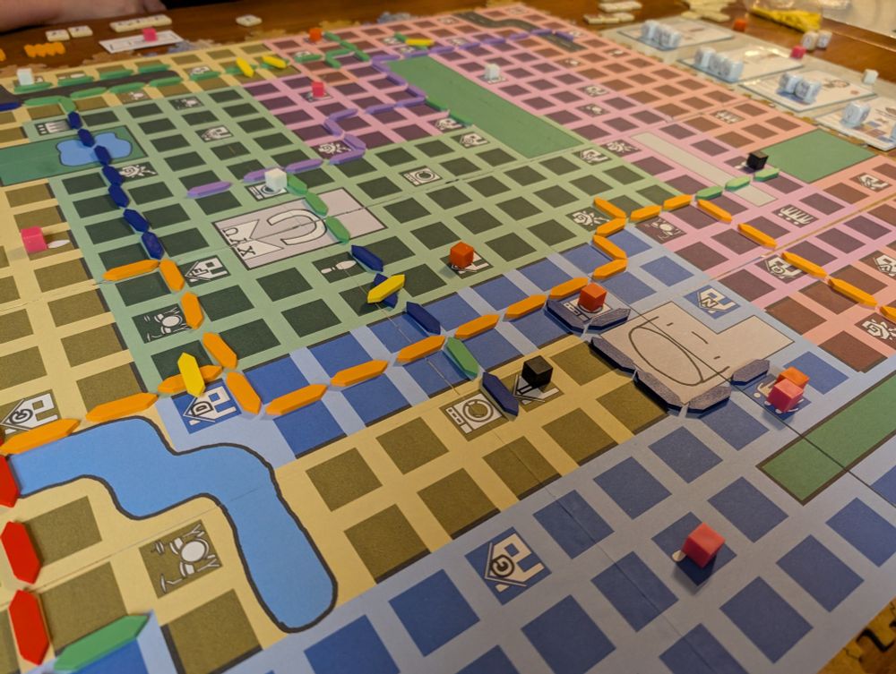 A game map with various colored zones on it. There are several colors of game pieces on the map making routes throughout the map.