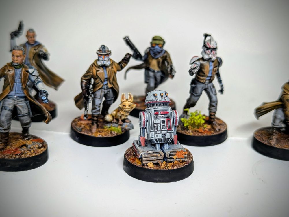 An Astromech miniature Infront of sleeper cell miniatures kitbashed with clone armour parts.