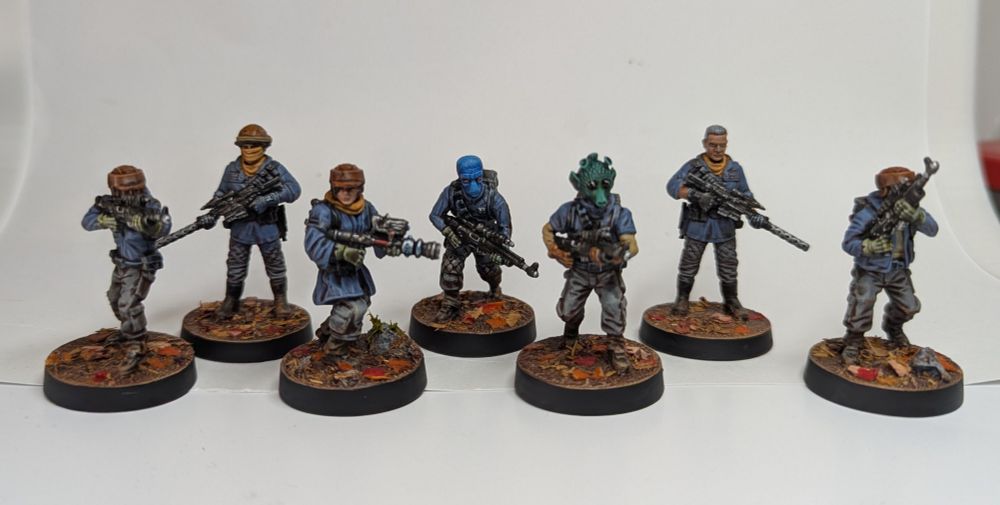 A group of rebel trooper miniatures - blue and grey fatigues with orange spot colour on autumn foliage bases.