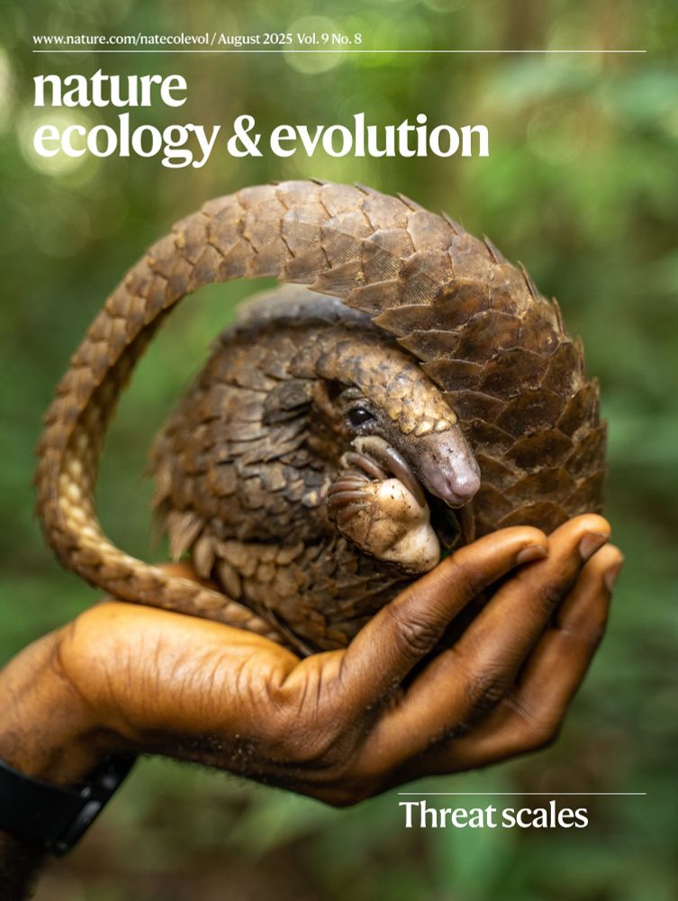 Cover of the August issue of Nature Ecology & Evolution. The image shows a pangolin curled up in a ball in the palm of a hand. The headline reads "Threat scales"