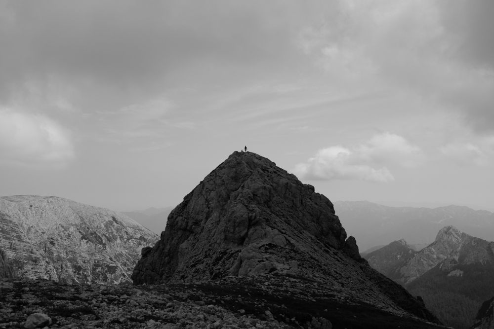 23mm black and white photograph of my friend standing atop a peak in the slovenian mountain range in triglav national park