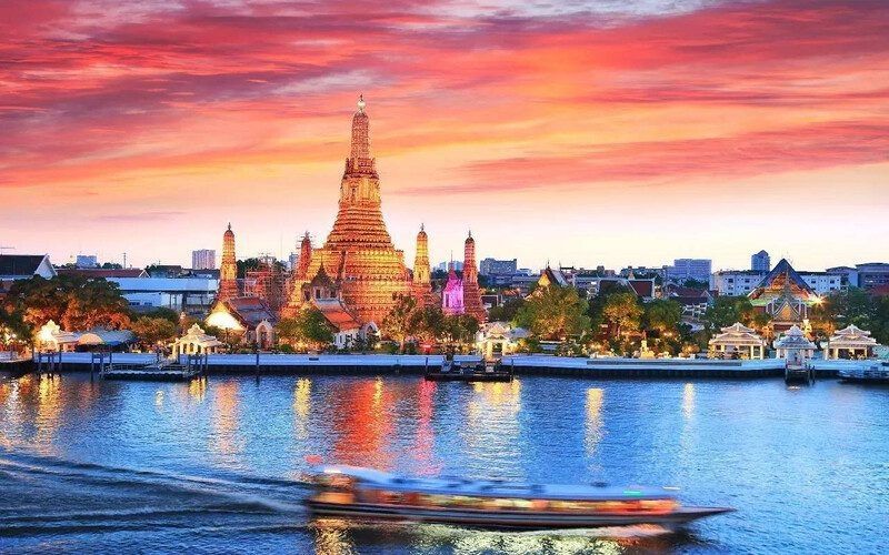 Soleil couchant sur Bangkok / mais ça marche aussi pour dire bonjour !
le temple wat Arun domine le fleuve Chao Phraya sur lequel file au 1er plan une pirogue chargée éclairée trouble
Sous un ciel en flammes 