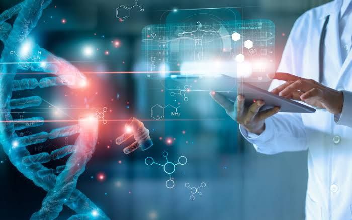 A imagem mostra uma pessoa, provavelmente um cientista ou médico, usando um jaleco. No primeiro plano, há uma representação gráfica de uma molécula de DNA sendo manipulada por um tablet. A pessoa está no canto direito da imagem, enquanto o foco da imagem está nas cadeias de DNA a esquerda. Além disso, há uma rede de conexões, sugerindo conceitos de biotecnologia, manipulação genética ou edição de DNA, em um ambiente de laboratório altamente tecnológico.