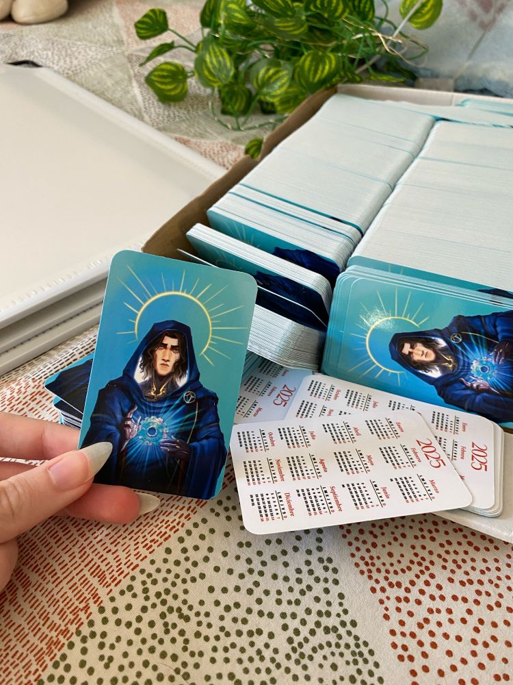Fotografía de unas estampitas con la imagen de Viktor de arcane como un santo y por detrás es un calendario de 2025