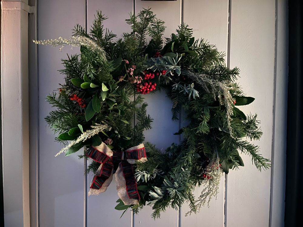 Holiday wreath made from California native plants and red pyracantha berries sporting a red and gold bow
