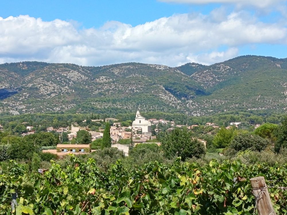 The village nestling under green hills. A white Spanish church crowns the hill in the distance. 