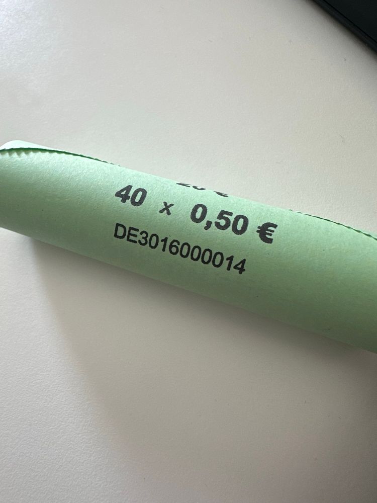 A close up shot of a roll of 50 cent pieces on a white table. Wrapped in green paper. It says "40 x 0,50 €" + a serial(?) number.