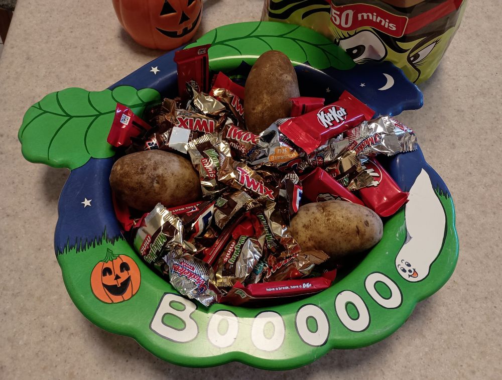 Bowl of candy with three potatoes stuck in it