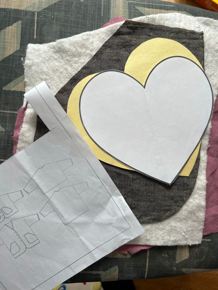 Two heart templates rest on top of a quilt sandwich the size of a pocket. The Muna and Broad Grainger Coat is to the side.
