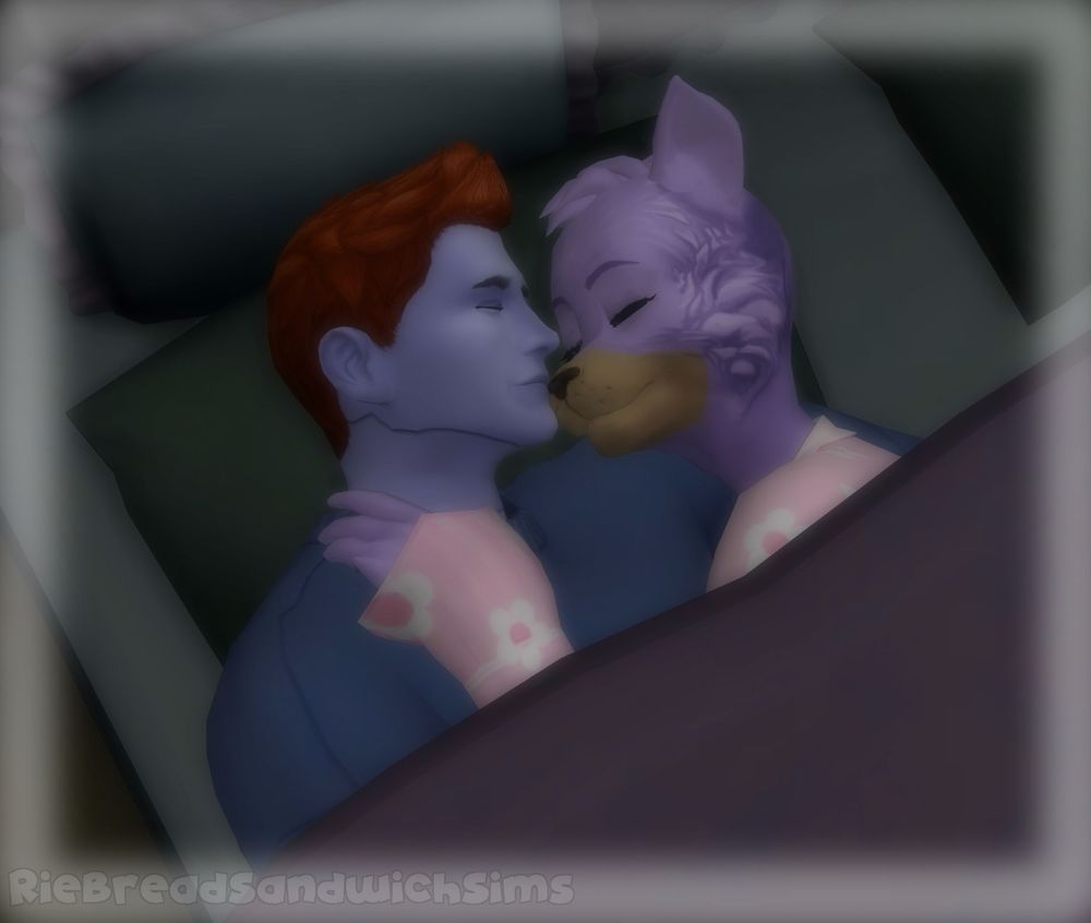 A screenshot of The Sims 4, two characters are laying in a bed together, on the left is a periwinkle colored humanoid robot with an orange faux hawk. On his right is a lavender cat wearing pink pajamas with a white flower pattern.

The two of them are fast asleep in each other’s arms, cuddling close.

There is a dreamy glow effect on the screenshot, indicating this is a dream of the cat.