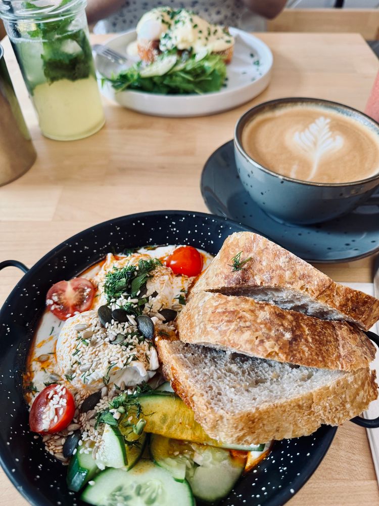 Pochierte Eier mit griechischen Joghurt Chili Tomaten Gurken Körnerzeug und köstliche Brot 