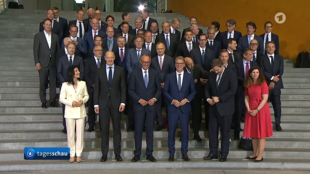 Screenshot Tagesschau Unternehmer, Merz, Frau Reiche, 1 weitere Frau, Aufstellung auf Treppe zum Foto