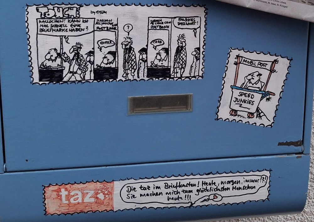 Ausschnitt: Briefkasten mit aufgemalten Kopien von touché-Comics, dem taz-Emblem und einem Text: "Die taz im Briefkasten! Heute, morgen, immer?!? Sie machen mich zum glücklichsten Menschen heute!!!"