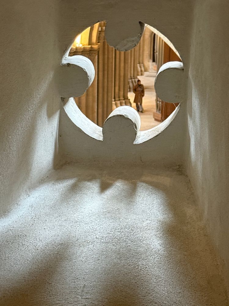 Durch eine über dem Kirchenschiff befindliche Öffnung in der Wand schaut man von oben ins Schiff hinein. Blick auf die Säulen und einen Menschen. 