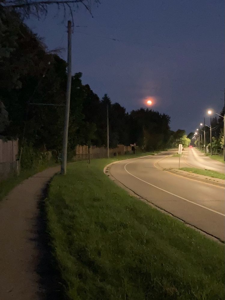 Red tinged moon rising over an empty street